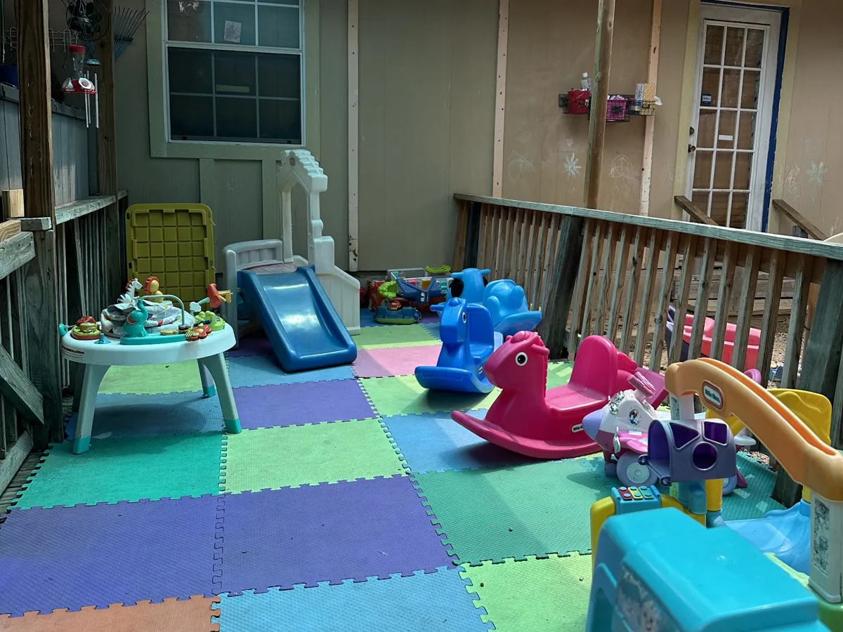 Shaded play patio with soft foam mats and toddler toys
