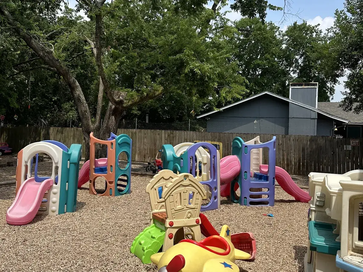 Outdoor playground with slides, climbers and ride-on toys at Little Explorers Child Care